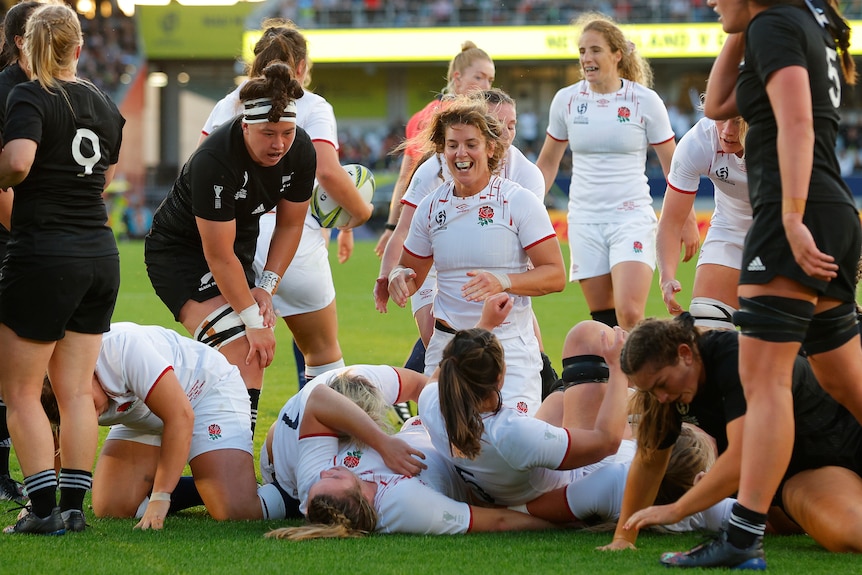 Amy Cokayne celebrates behind a pile of bodies after a maul