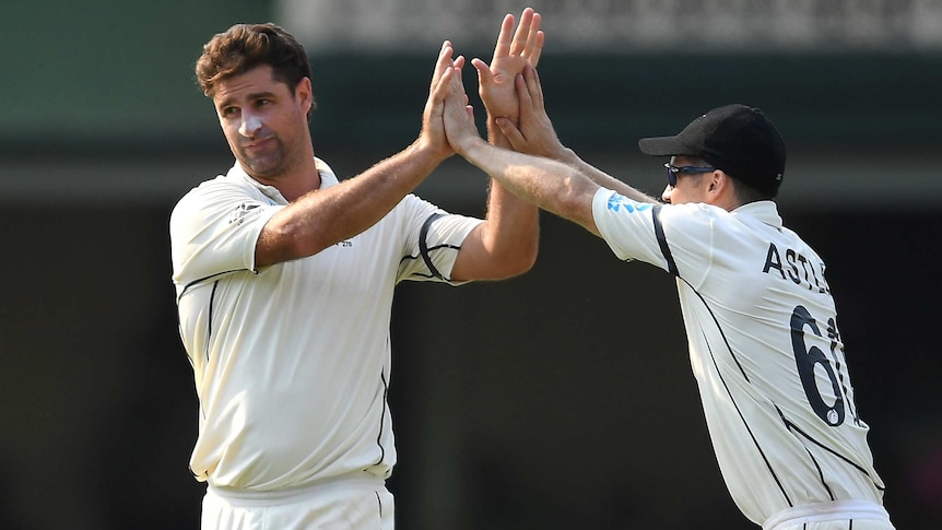 Two New Zealand cricketers celebrate after taking a wicket.