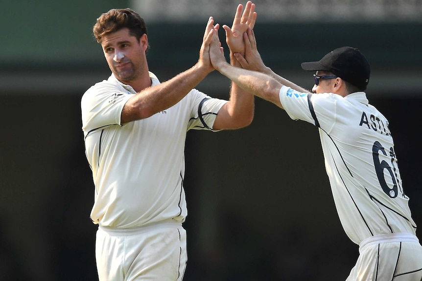 Two New Zealand cricketers celebrate after taking a wicket.