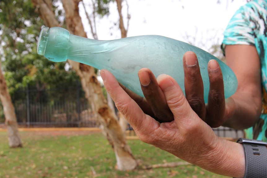 The two women hold the bottle for the camera.