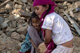 Two young girls move debris in Nepal from their collapsed home
