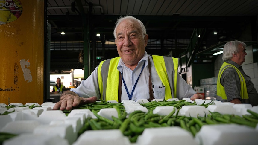 Fruit and vegetable wholesaler Joe Antico smiling at the camera, leaning over a crate of beans.