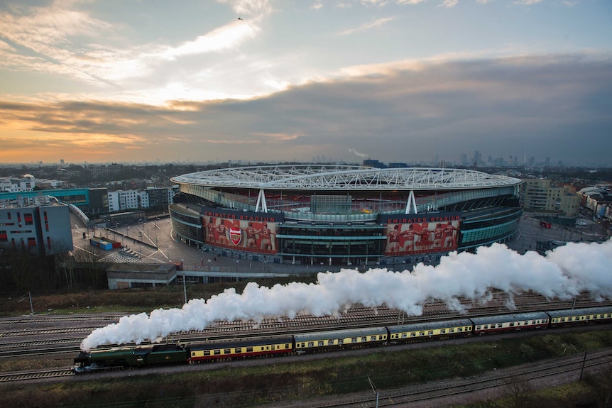 Aerial view of the Flying Scotsman, steam billowing, as it passes the Emirates Stadium in London.