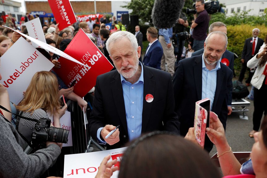 Jeremy Corbyn signs placards at a campaign event.