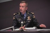 Tasmania Police's Darren Hine speaks from a table.