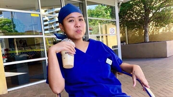 Judy Ann Imperial sitting drinking an iced coffee, while wearing her aged care uniform. 