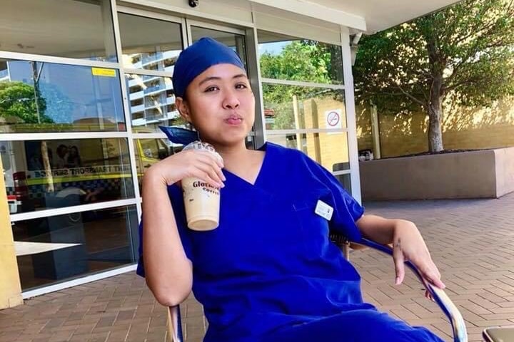 Judy Ann Imperial sitting drinking an iced coffee, while wearing her aged care uniform. 