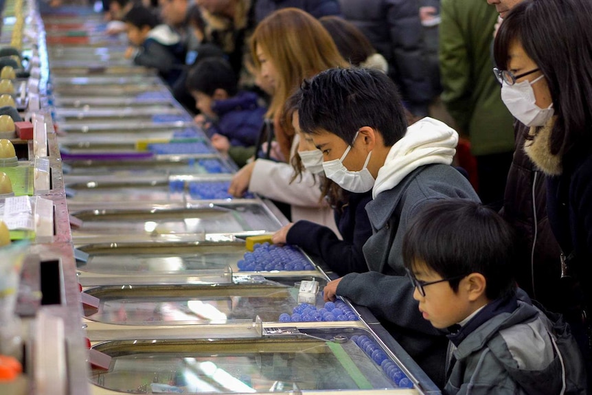 People play on a long row of smart ball machines.