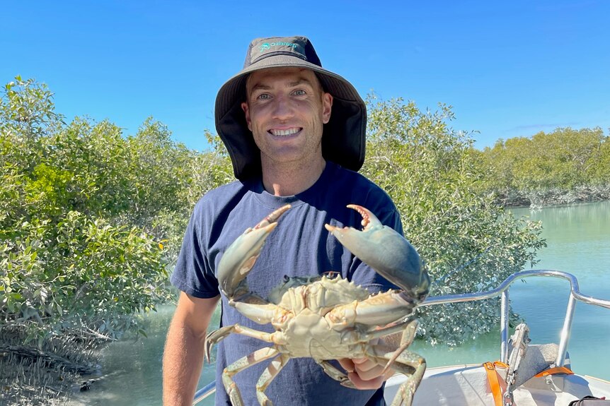 Brad Sheppard holds a crab on a waterway in the Kimberley