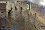 Staff wade through a flooded terminal at Auckland Airport