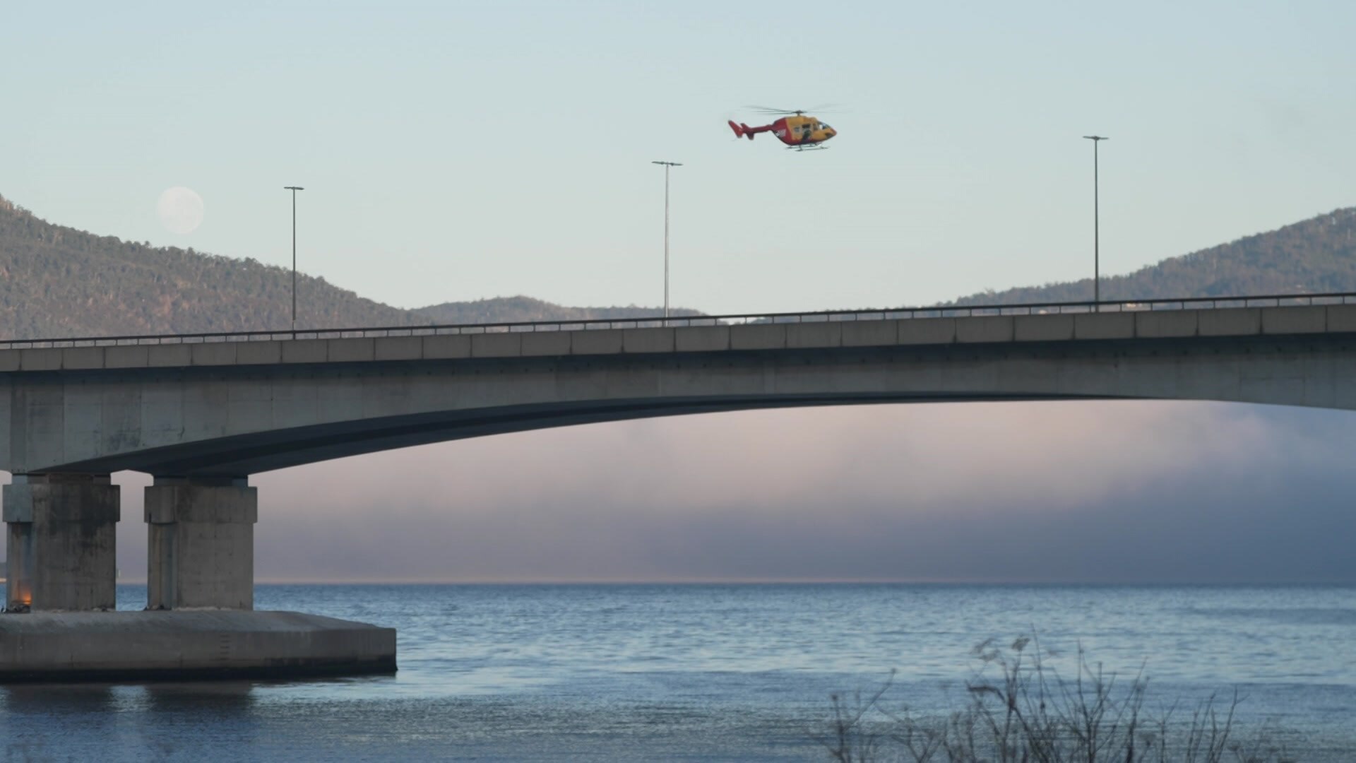 Helicopter in the sky above a bridge.