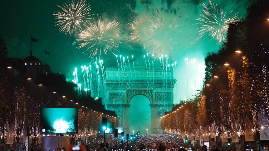 Revellers photograph fireworks over the Arc de Triomphe as they celebrate on the Champs Elysees.