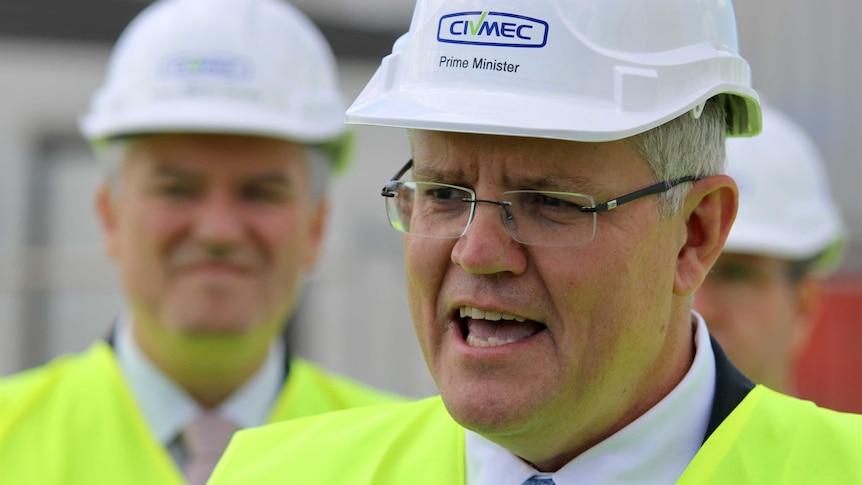 A head and shoulder shot of Prime Minister Scott Morrison speaking wearing a white hard hat and a hi-vis vest.
