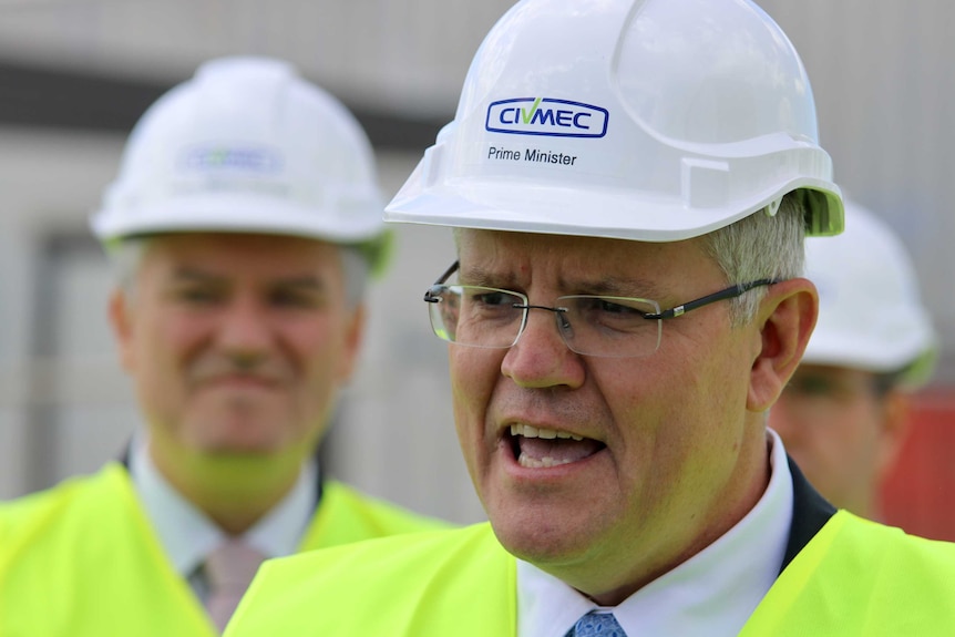 A head and shoulder shot of Prime Minister Scott Morrison speaking wearing a white hard hat and a hi-vis vest.