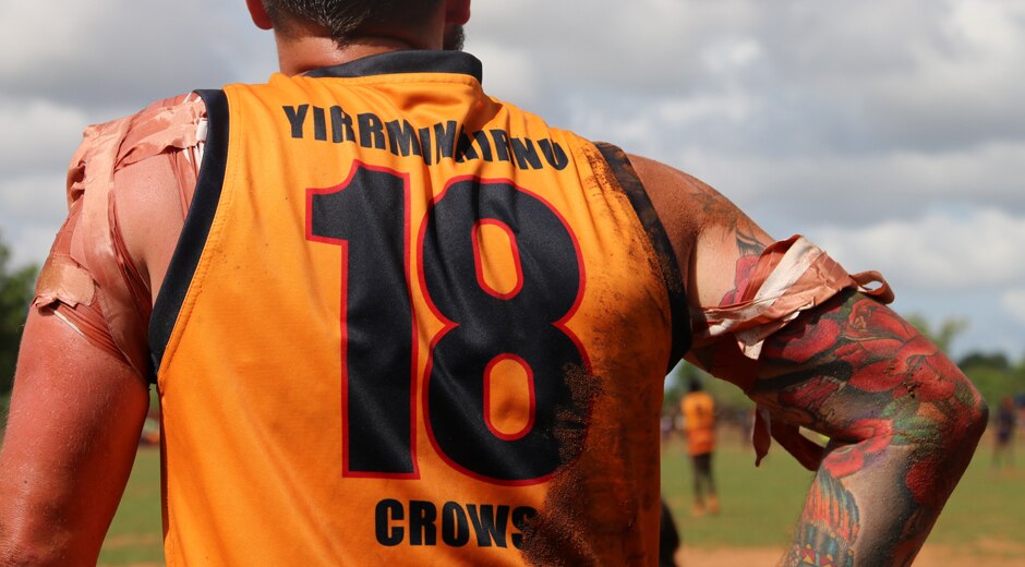 A bandaged-up Crows player stands at the sidelines.