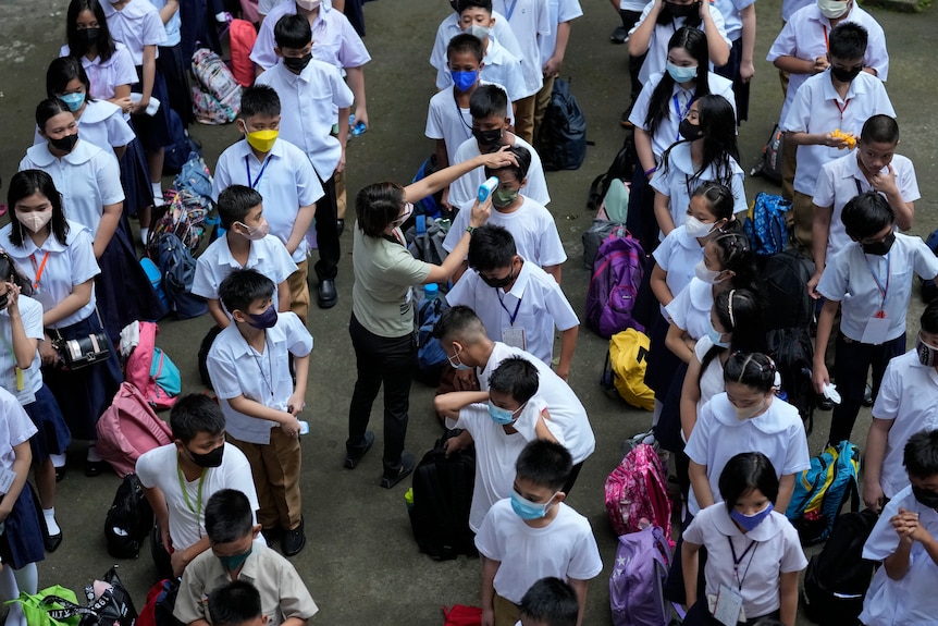  teacher conducts temperature checks on students during the opening of classes at the San Juan Elementary School 