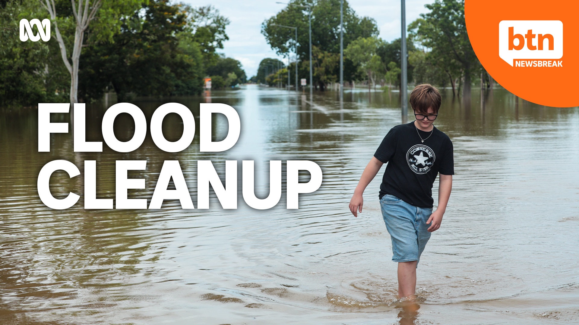 Person walking through floodwaters with the words flood cleanup.