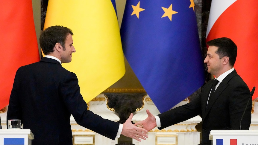 Ukrainian President Volodymyr Zelenskyy, right, and French President Emmanuel Macron go to shake hands.