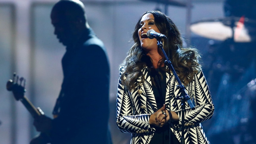 Alanis Morissette singing at a live performance. 