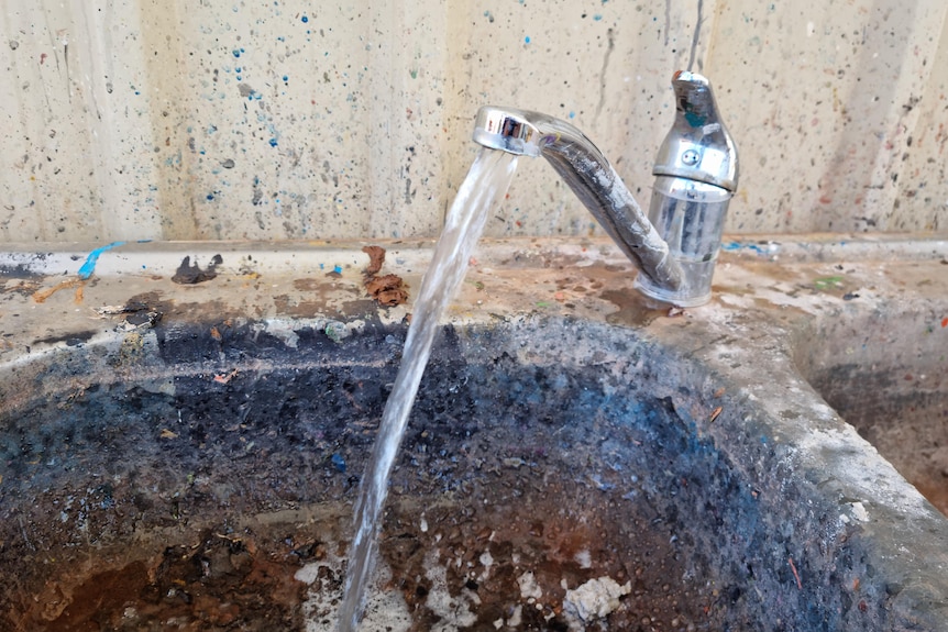 A running tap into a rusted sink.