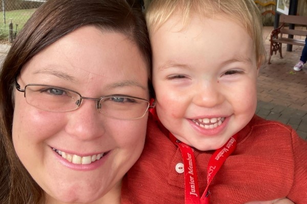 A mother and her son smile at the camera.