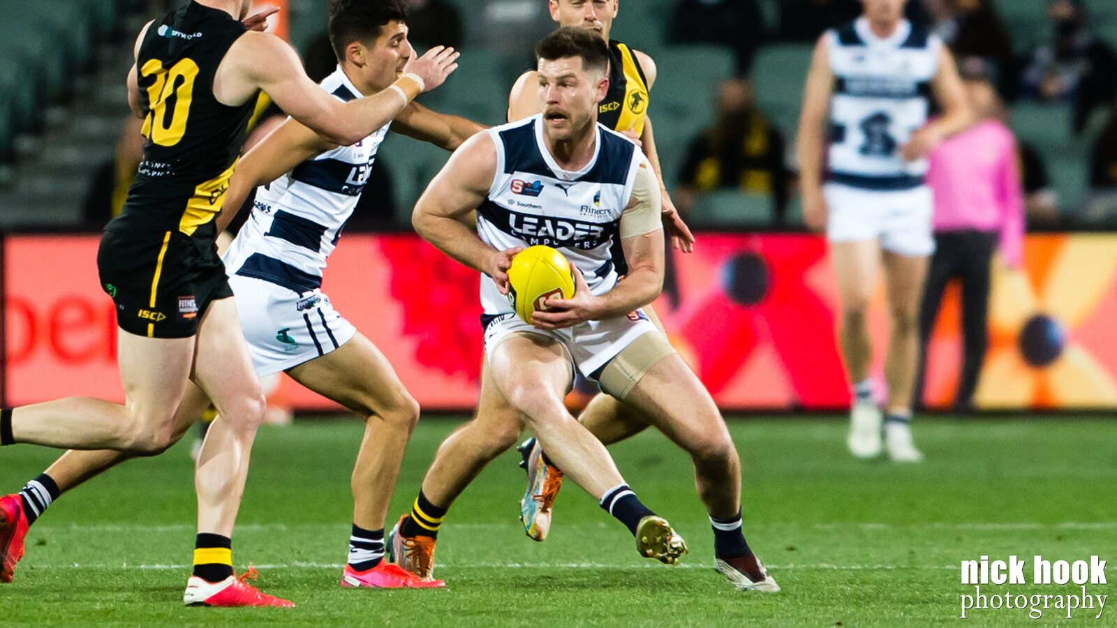 A football player crouches with a yellow ball while surrounded by other players