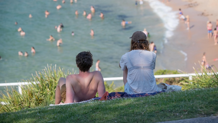 People at Coogee beach in Sydney sitting on the grass area overlooking the beach