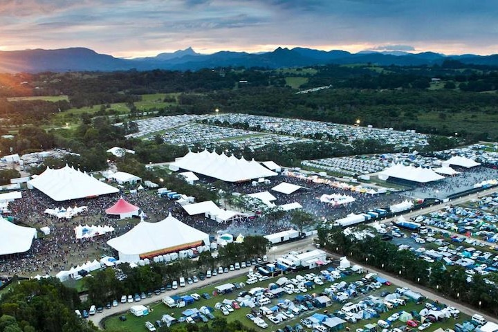 A drone shot of tents, cars and stages at a festival site.