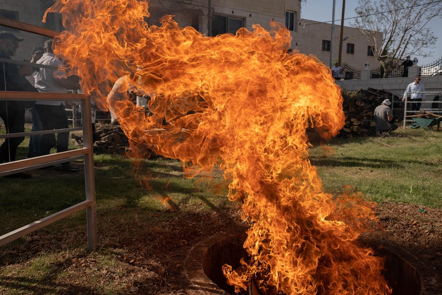 Flames billow out of a fire pit 