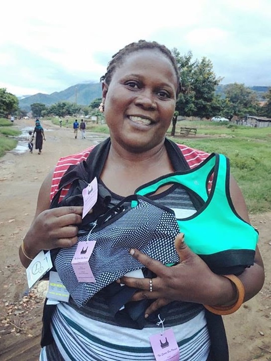 Margret Kunahimbrie holds sports bras while standing on a dirt road.