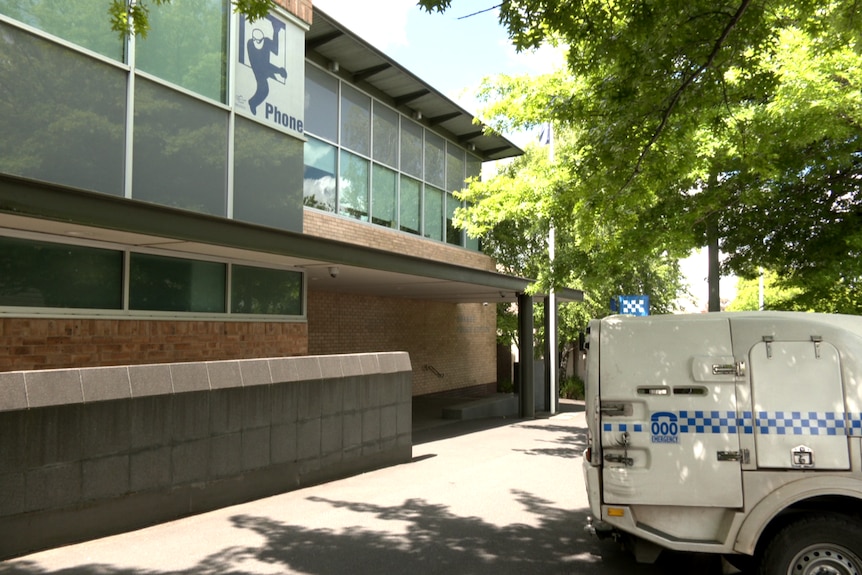 A police vehicle in the foreground outside a police station.