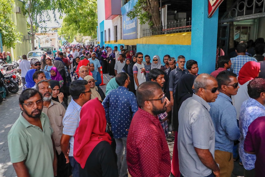 Queues of Maldivian men and women wait in line