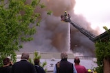 Shoppers watch on as firefighters in a cherry picker douse a fire from above