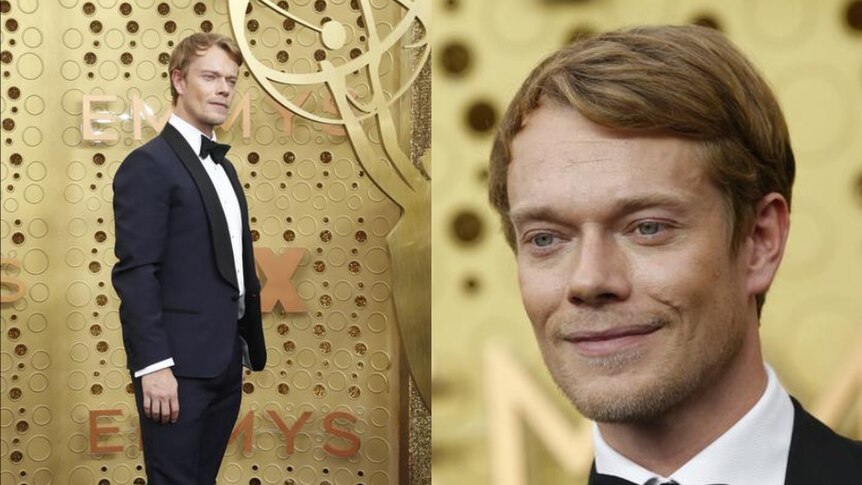 Alfie Allen wears a dark suit as he looks into a camera not seen on screen. The background behind him is gold.