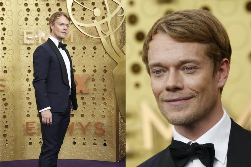 Alfie Allen wears a dark suit as he looks into a camera not seen on screen. The background behind him is gold.