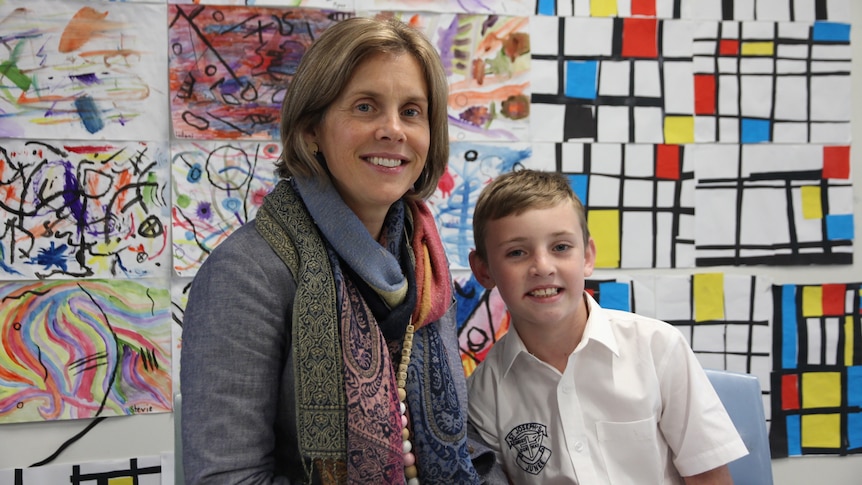Bianca Brady sat next to son Archer, 8, in front of a colorful backdrop of children's artworks.