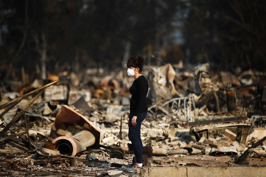 A woman surveys the wreckage where her home used to be after it was destroyed by wildfires in California.