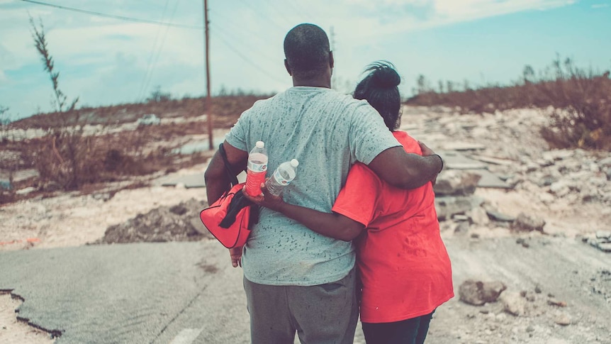 A couple in the Bahamas hug while standing on a road destroyed by Hurricane Dorian