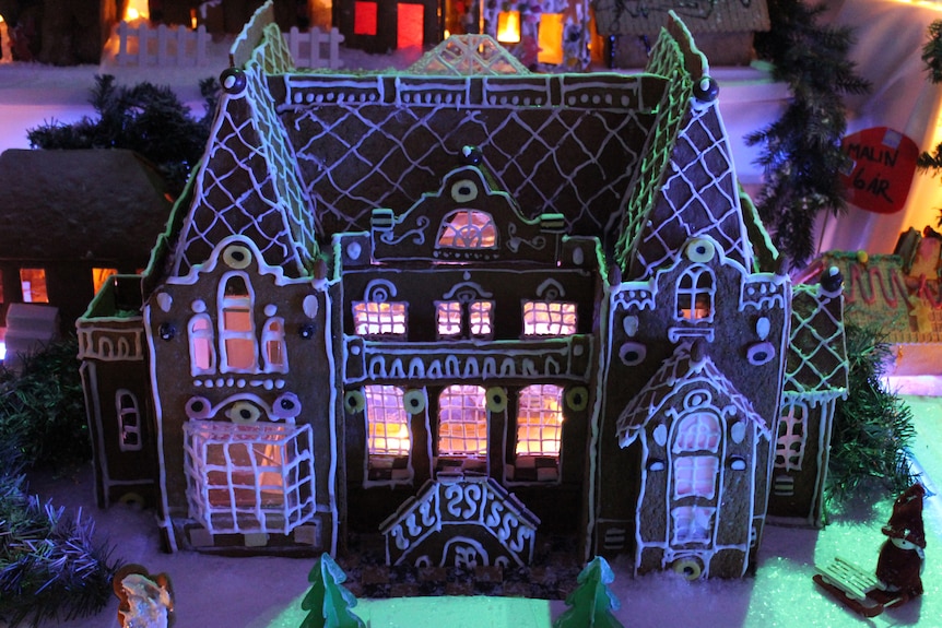 A close up image shows a model gingerbread castle that's decorated with sweets and icing.