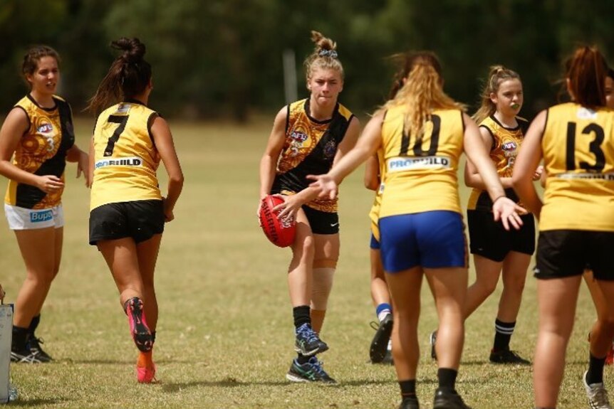 Marissa Williamson-Pohlman playing Australian rules football, with ball in hand, surrounded by opponents