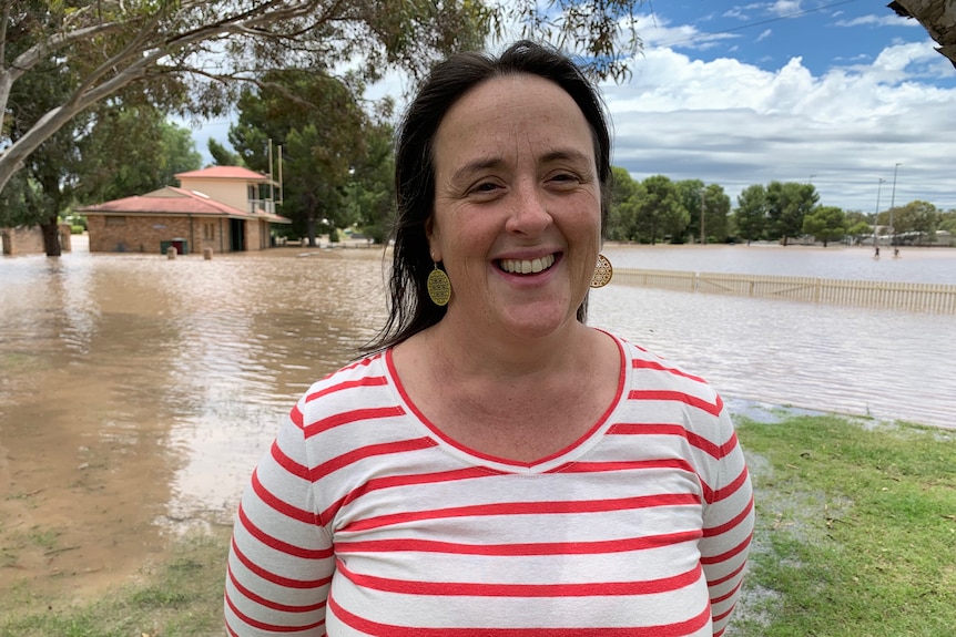 A woman in a striped red and white t shirt in front of muddy brown water.