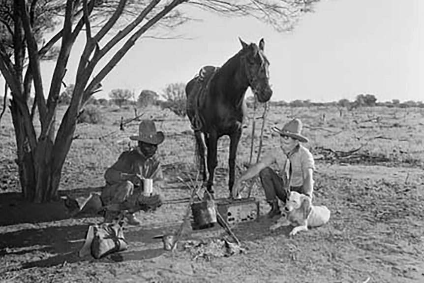 A black-and-white archival photo of a policeman and a tracker boiling a billy of tea.