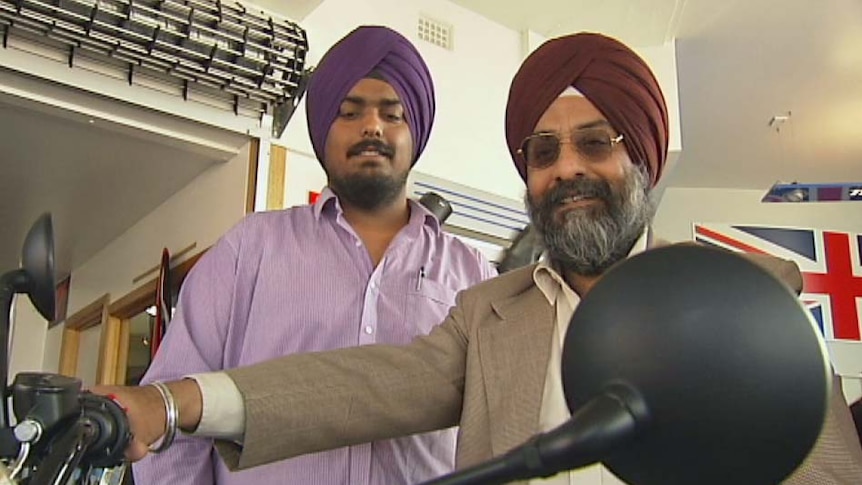Sikh Harpreed Singh inspects a motorbike with his son but he first wants to have helmet laws changed in Tasmania.