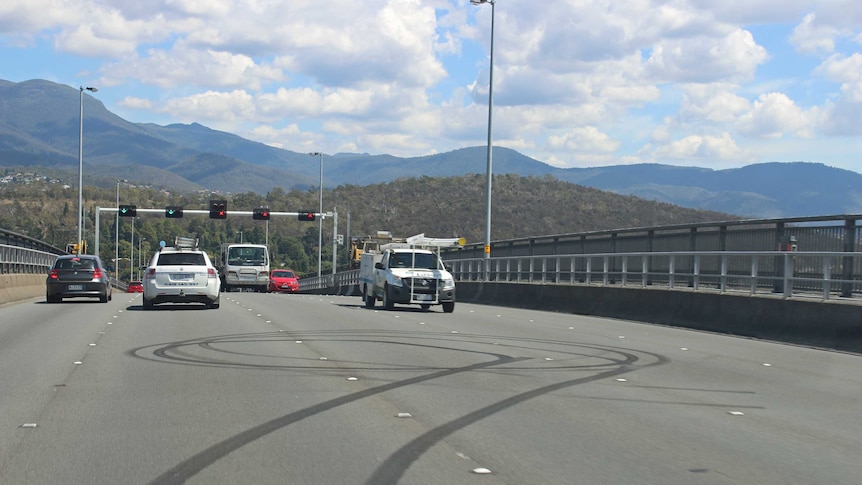 Daytime traffic passes the burnout marks on the apex of the Tasman Bridge.