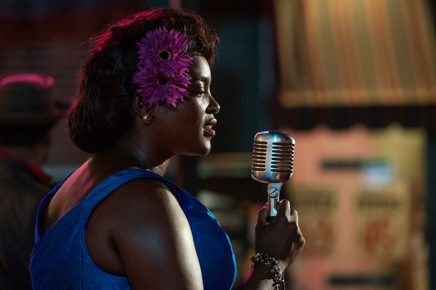 Actor Wunmi Mosaku singing into a microphone in 50s America in the TV show Lovecraft Country