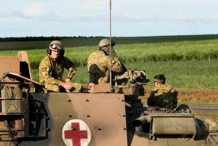 Army vehicle, with red cross on side, and soldiers.