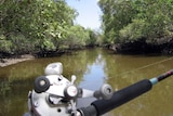 A fisherman sits with his rod and reel