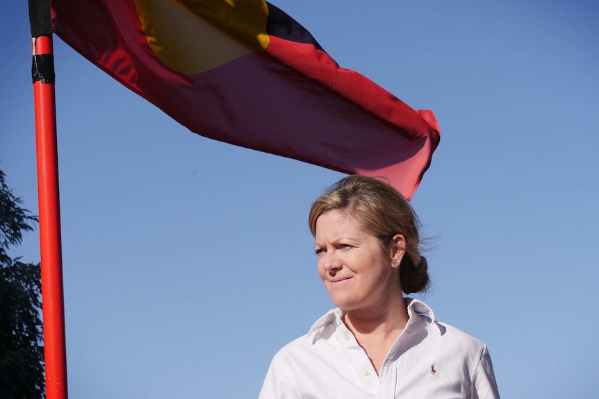 Angela Dos Santos poses for a portrait under an Indigenous flag