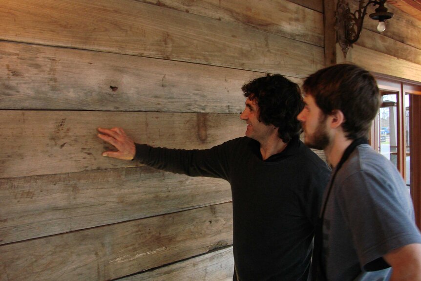 Two men look at recycled timber on a building in Griffith, New South Wales.