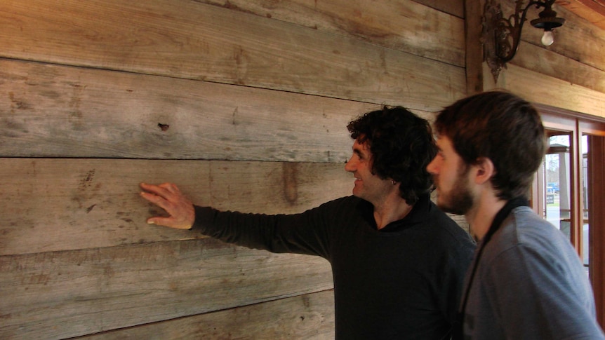 Two men look at recycled timber on a building in Griffith, New South Wales.